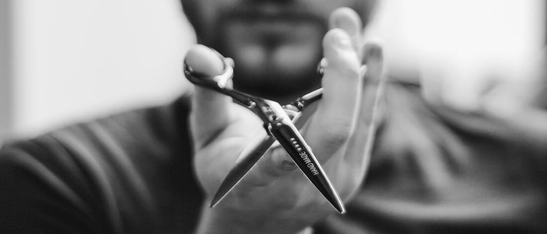 Black and white photo of a man holding hairdressing scissors.