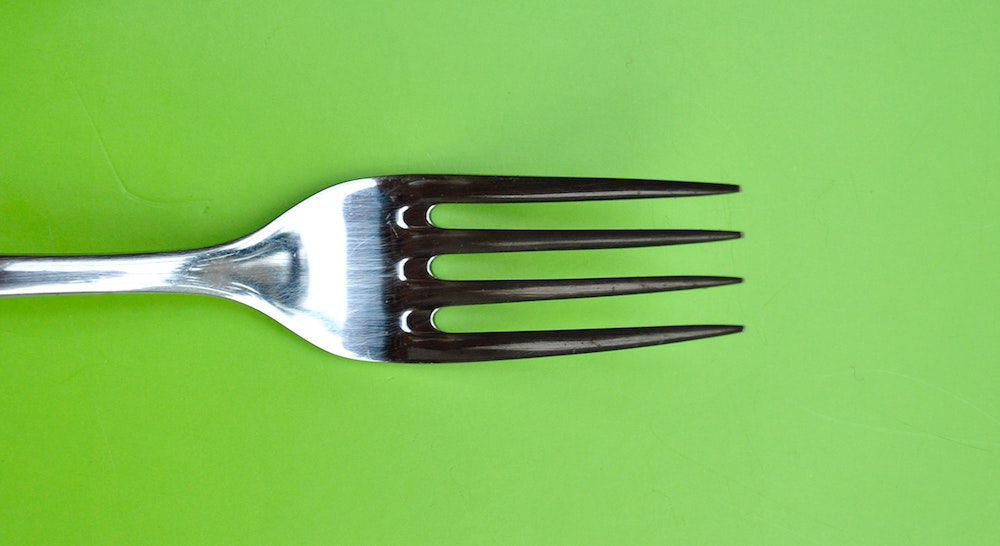 Close-up of a kitchen fork on a green background