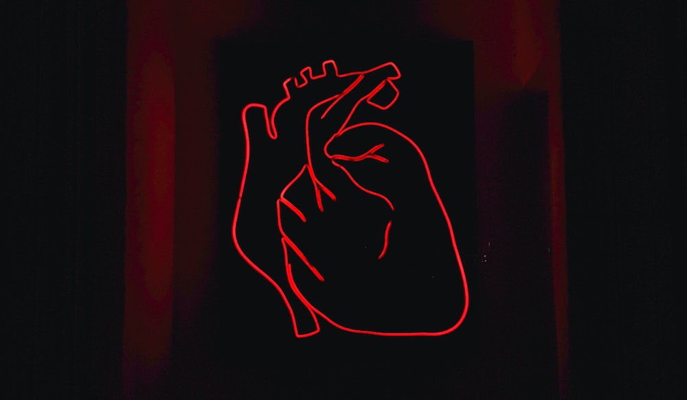Red neon outline of a human heart.