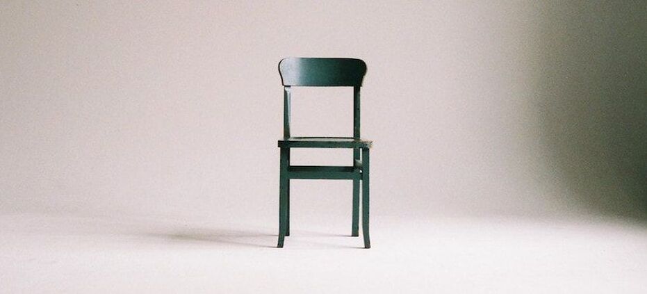 A solitary wooden chair against a blank background.