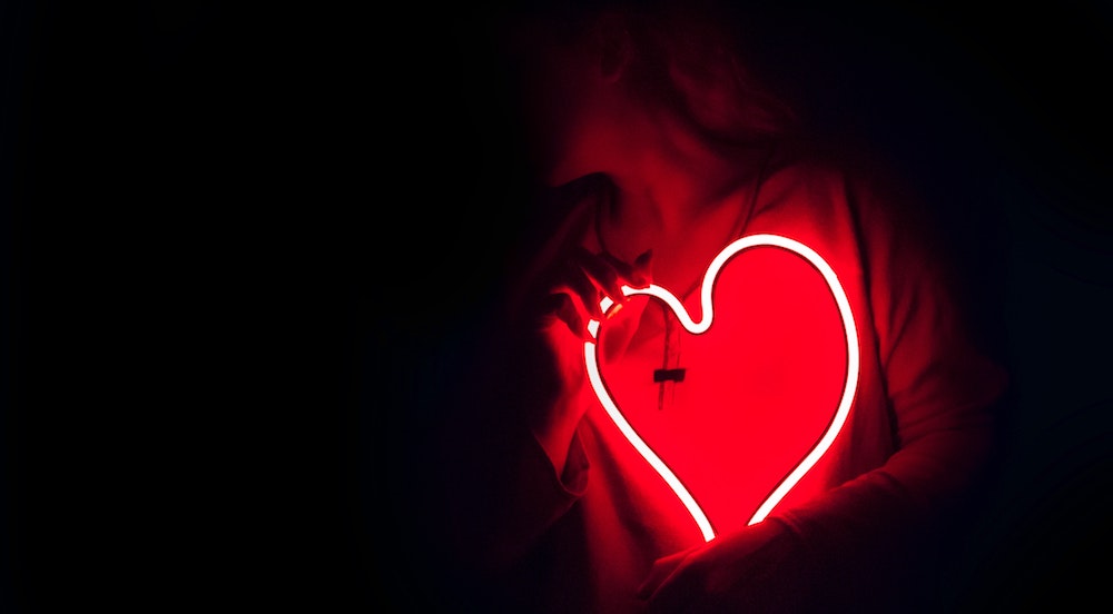 A woman holding a red neon heart