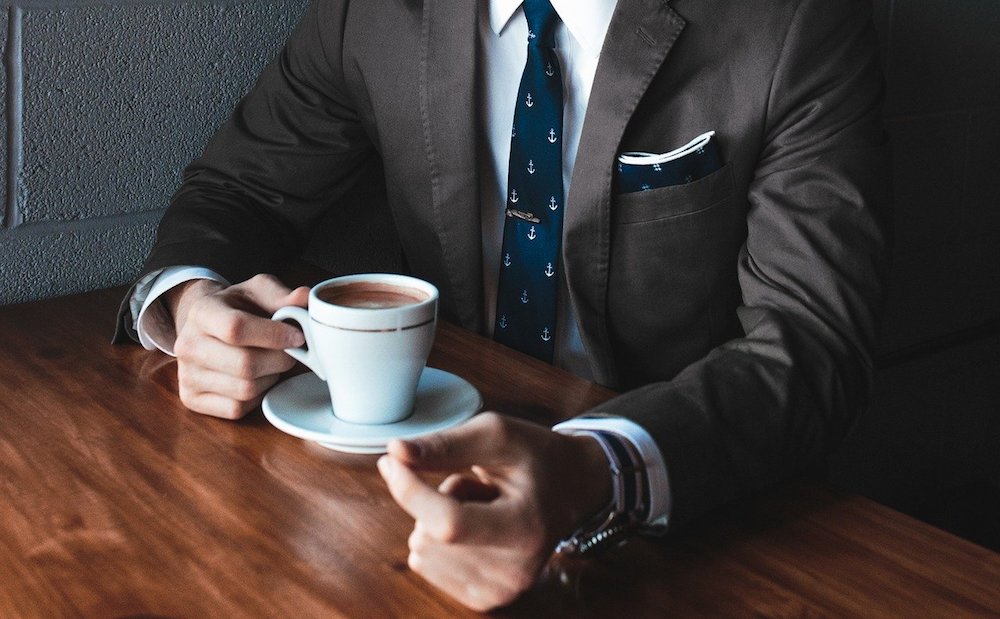 A well-dressed man holding a cup of coffee